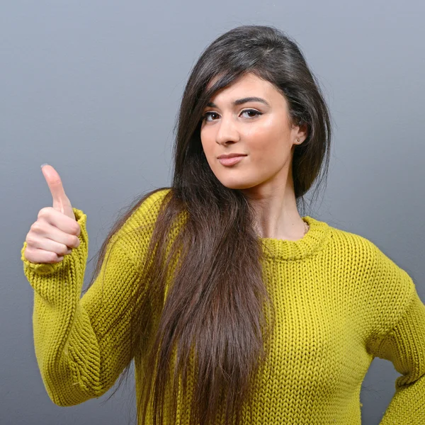 Retrato de mujer feliz sosteniendo pulgares contra fondo gris — Foto de Stock