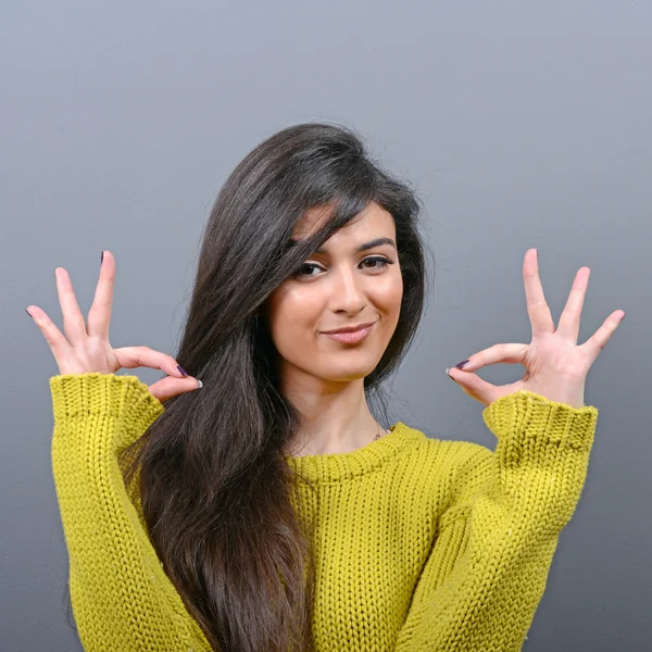 Portrait of happy woman showing ok sign against gray background — Stock Photo, Image