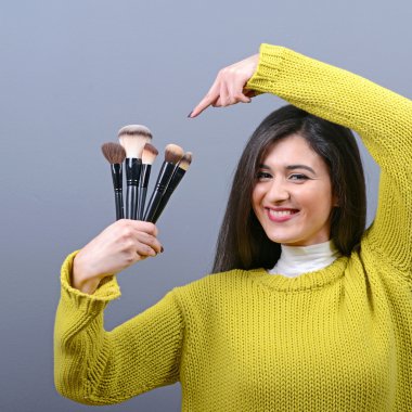 Makyaj fırçaları karşı gri adam tutan kadın portresi