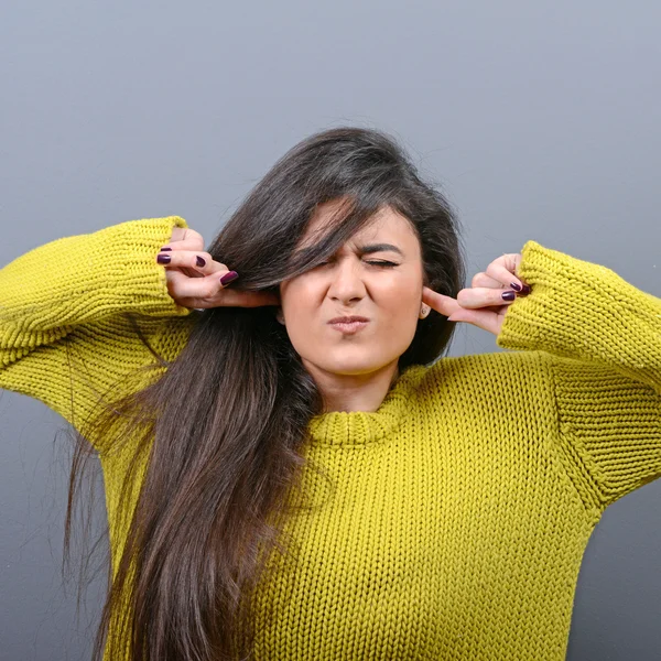 Retrato de mujer cubriendo orejas con las manos contra el fondo gris —  Fotos de Stock