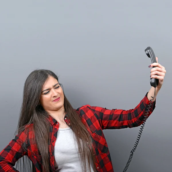 Portrait of woman having unpleasant phone calll against gray bac — Stock Photo, Image