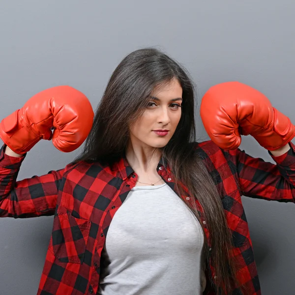 Retrato de mujer joven posando con guantes de boxeo contra gris b — Foto de Stock