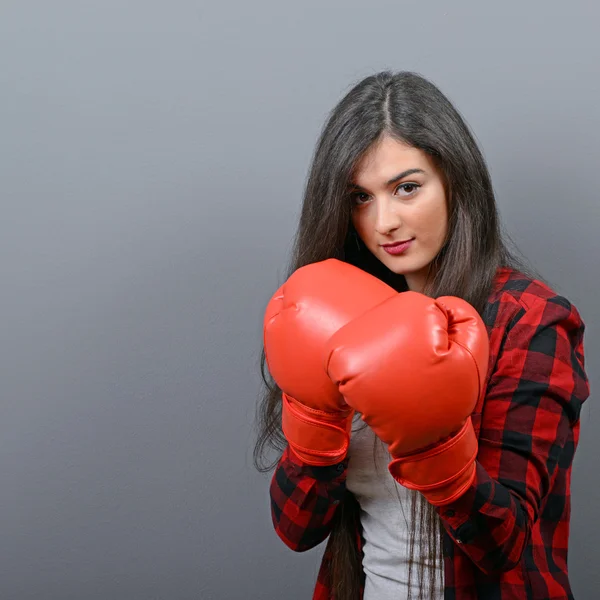 Retrato de mujer joven posando con guantes de boxeo contra gris b — Foto de Stock