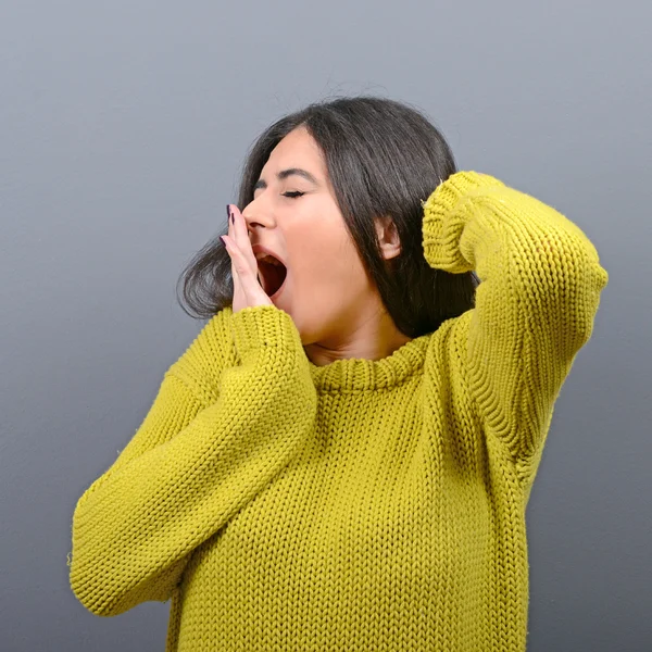 Retrato de mujer joven estirándose y bostezando contra la espalda gris —  Fotos de Stock