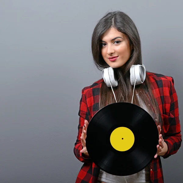 Pretty female DJ with headphones and vinyl against gray backgrou — Stock Photo, Image