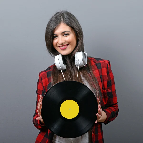 Pretty female DJ with headphones and vinyl against gray backgrou — Stock Photo, Image