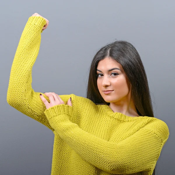 Jolie jeune femme brune montrant biceps sur son bras contre gra — Photo