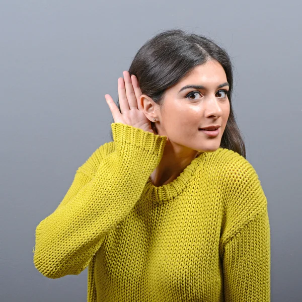 Woman listening with hand to ear concept against gray background — Stock Photo, Image