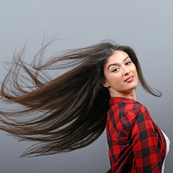 Mujer joven moviendo su pelo y posando sobre fondo gris — Foto de Stock