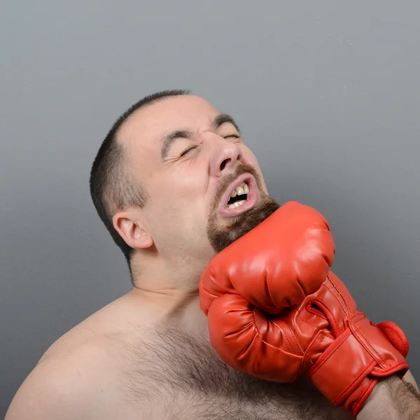 Portrait of funny fat boxer getting punch in face against gray b