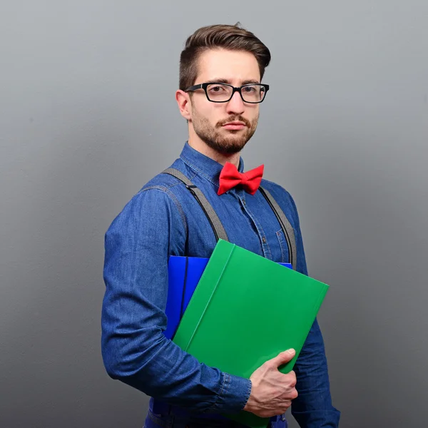Pohledný mladý podnikatel drží poznámky proti šedé pozadí — Stock fotografie