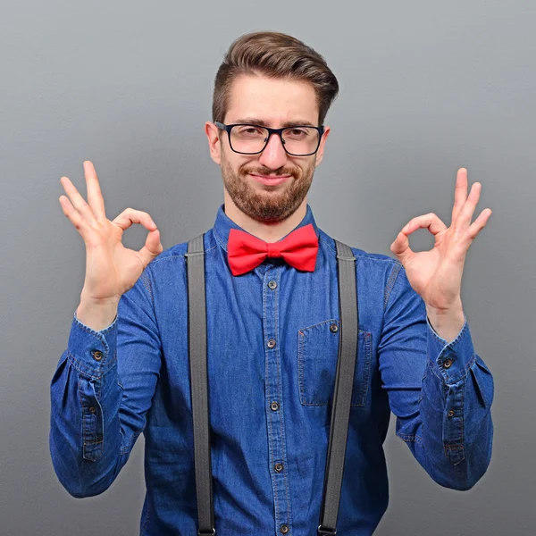 Portrait of a man showing ok sign against gray background — Stock Photo, Image