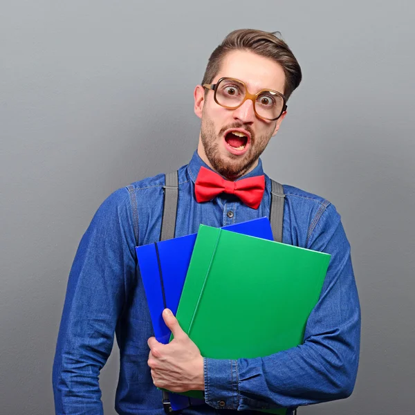 Portrait of a nerd holding books with retro glasses against gray — Stock Photo, Image