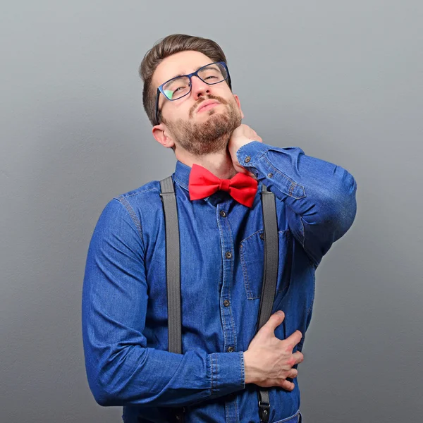 Portrait of man with neck pain against gray background — Stock Photo, Image