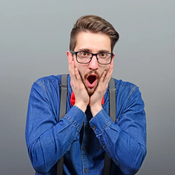 Portrait of shocked man against gray background — Stock Photo, Image