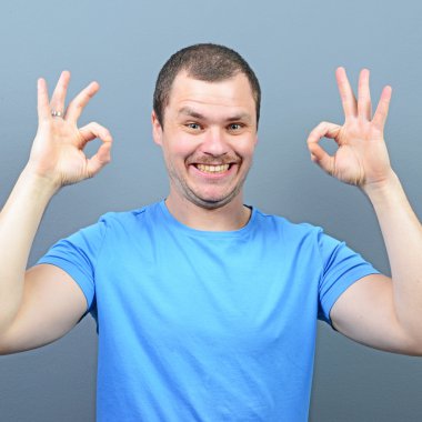 Başparmak yukarı veya ok işareti gri backg karşı gösterilen bir adam portresi