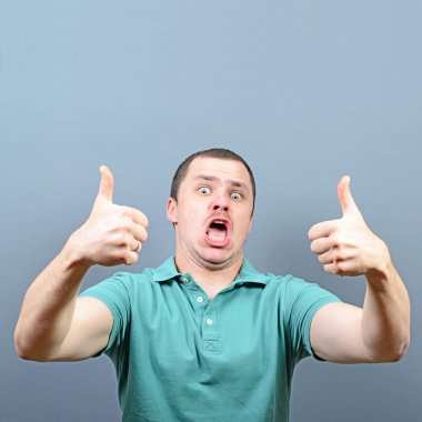 Başparmak yukarı veya ok işareti gri backg karşı gösterilen bir adam portresi