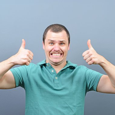 Başparmak yukarı veya ok işareti gri backg karşı gösterilen bir adam portresi