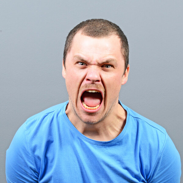 Portrait of a angry man screaming against gray background