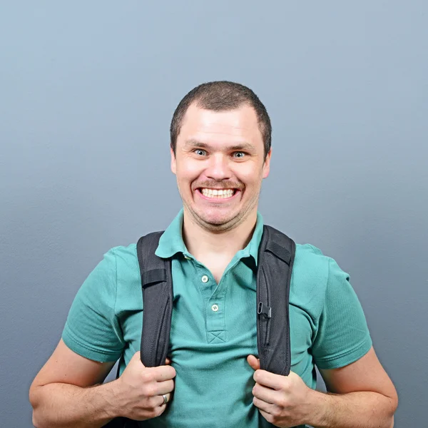 Portrait of a funny man with backpack against gray background — Stock Photo, Image