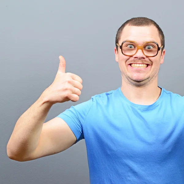 Portrait of a geek showing thumbs up against gray background — Stock Photo, Image