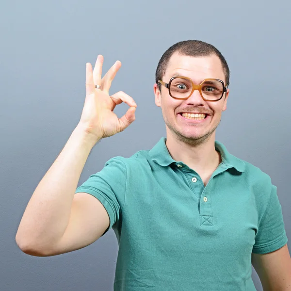 Portrait of a man showing ok sign against gray background — Stock Photo, Image
