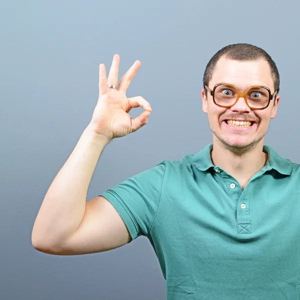 Retrato de un hombre mostrando signo aceptable contra fondo gris —  Fotos de Stock