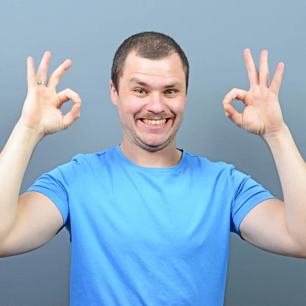 Retrato de un hombre mostrando el pulgar hacia arriba o signo de ok contra la espalda gris —  Fotos de Stock