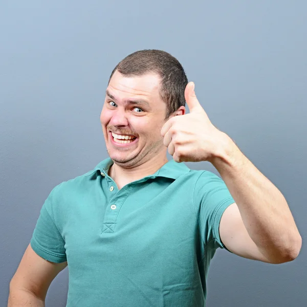 Portrait of a man showing thumb up or ok sign against gray backg — Stock Photo, Image