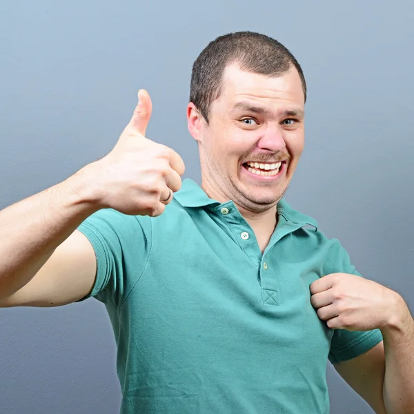 Portrait of a man showing thumb up or ok sign against gray backg — Stock Photo, Image