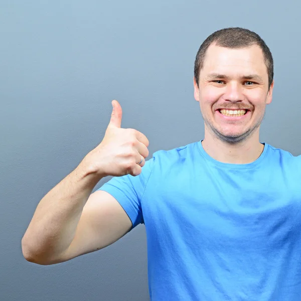 Portrait of a man showing thumb up or ok sign against gray backg — Stock Photo, Image