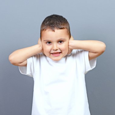 Sevimli küçük çocuk çocuk gri ba karşı elleriyle kulaklarını kapsayan