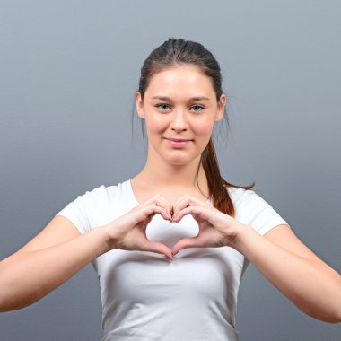 Kalp gri backgr karşı elinde tutan güzel mutlu kadın