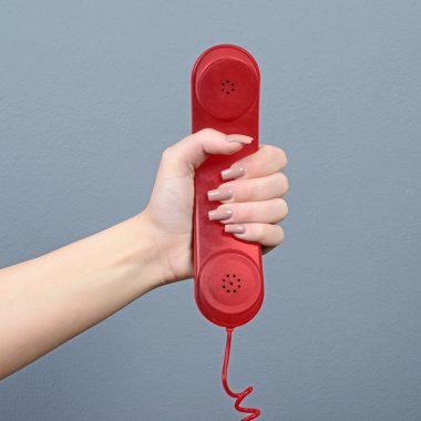 Gri arka planı kırmızı telefon tutarak el