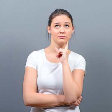 Yukarıdaki gri ba karşı arayan düşünceli genç kadın portresi