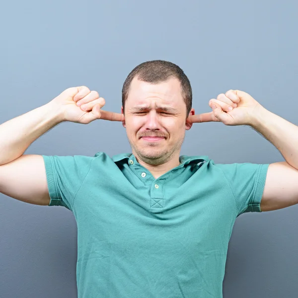 Porträt eines Mannes, der die Ohren mit den Händen vor grauem Hintergrund bedeckt — Stockfoto