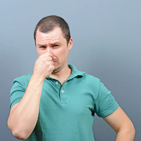 Portrait of man covering nose with hand showing that something s — Stock Photo, Image