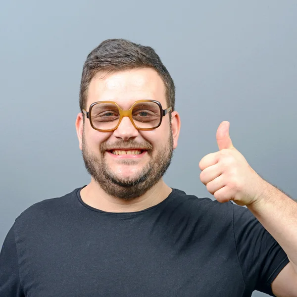 Portrait d'un geek potelé montrant les pouces vers le haut contre le dos gris — Photo