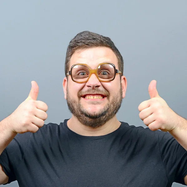 Portrait d'un geek potelé montrant les pouces vers le haut contre le dos gris — Photo