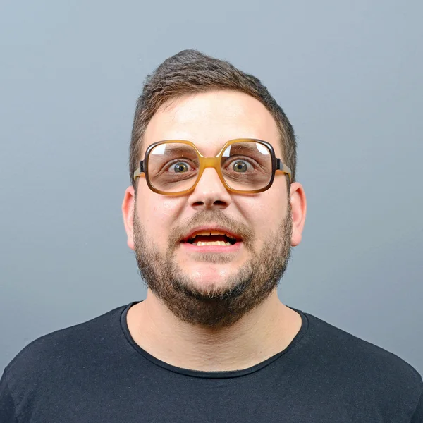 Portrait of a confused chubby geek against gray background — Stock Photo, Image