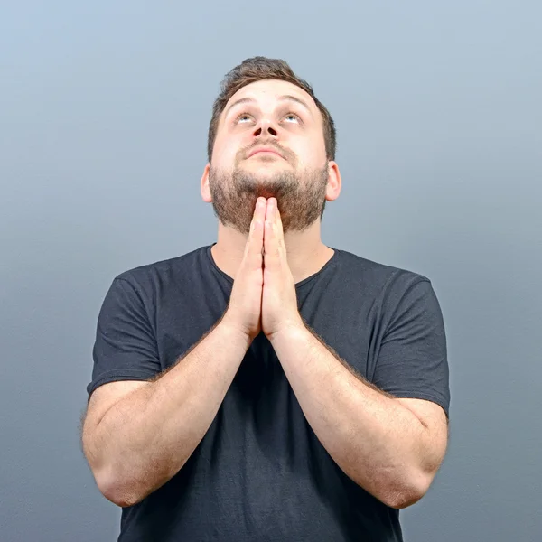 Ritratto di un uomo che prega su sfondo grigio — Foto Stock