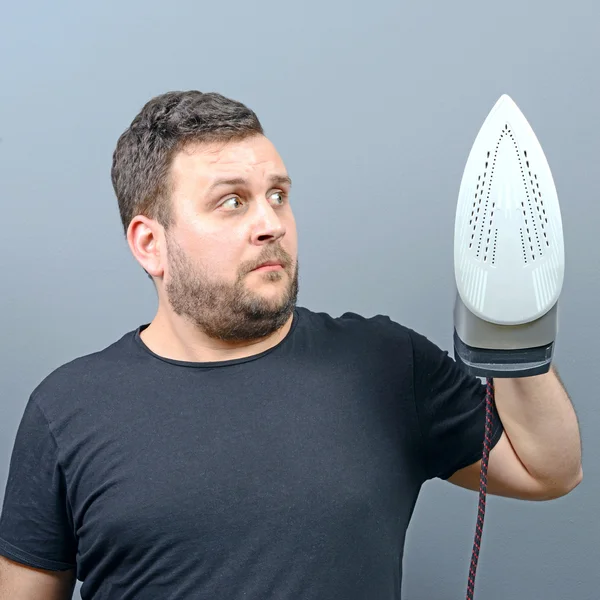 Portrait of a unhappy and confused man holding iron — Stock Photo, Image