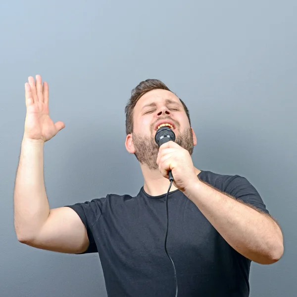 Portrait of attractive young man singer against gray background — Stock Photo, Image