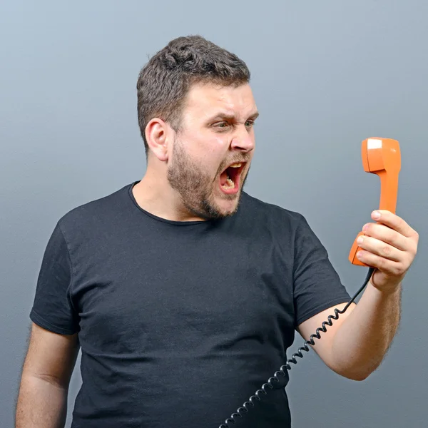 Retrato de hombre gordita divertido gritando en el teléfono contra bac gris —  Fotos de Stock