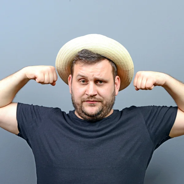 Portrait of funny chubby man wearing straw hat showing muscles — Stock Photo, Image