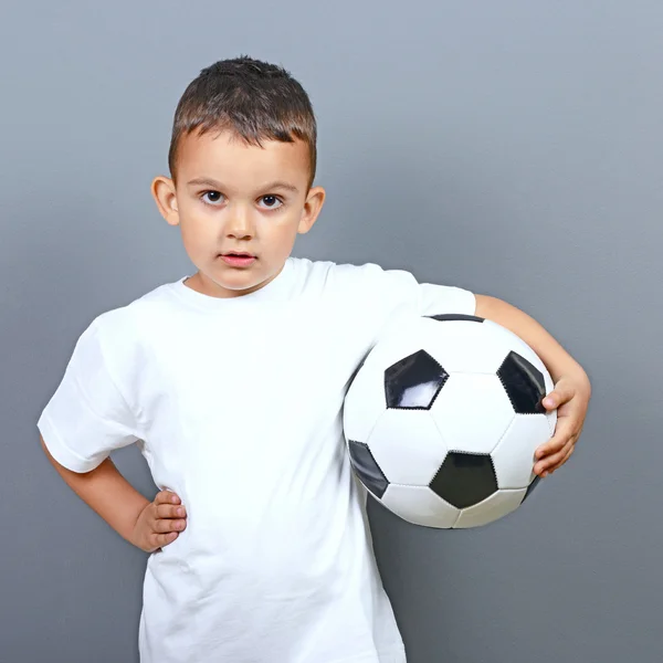 Mignon petit garçon posant avec football sur fond gris — Photo