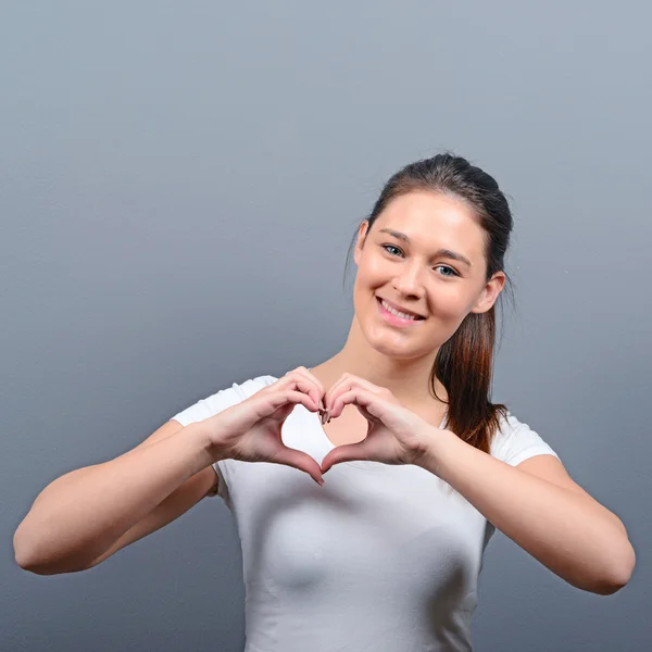 Hermosa mujer feliz haciendo corazón con las manos contra el respaldo gris —  Fotos de Stock