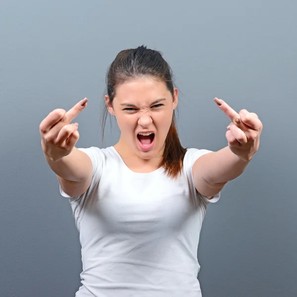 Portrait of a angry woman showing middle fingers against gray ba — Stock Photo, Image