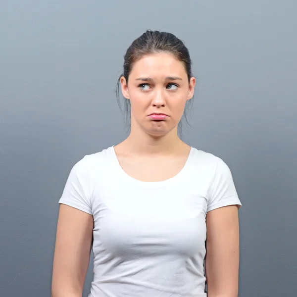 Portrait of a sad woman against gray background — Stock Photo, Image