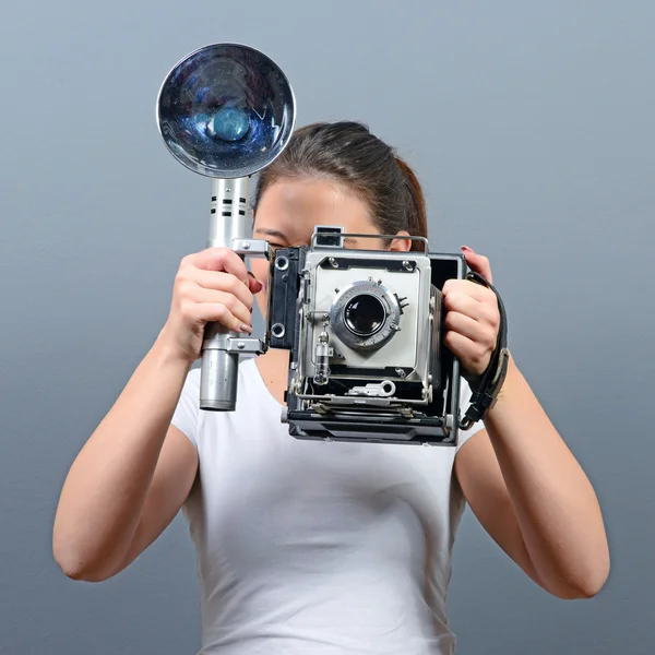 Retrato de uma jovem mulher, segurando a câmera retro cinza nas costas — Fotografia de Stock